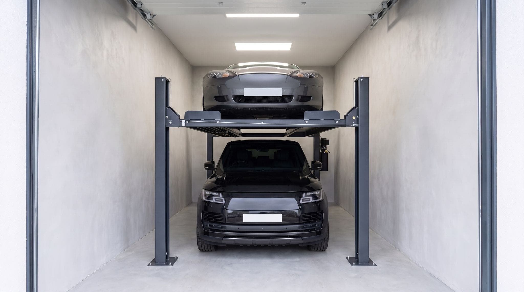 Doubleur de parking dans un garage individuel : coupé gris sur la plateforme haute, grand SUV noir en dessous